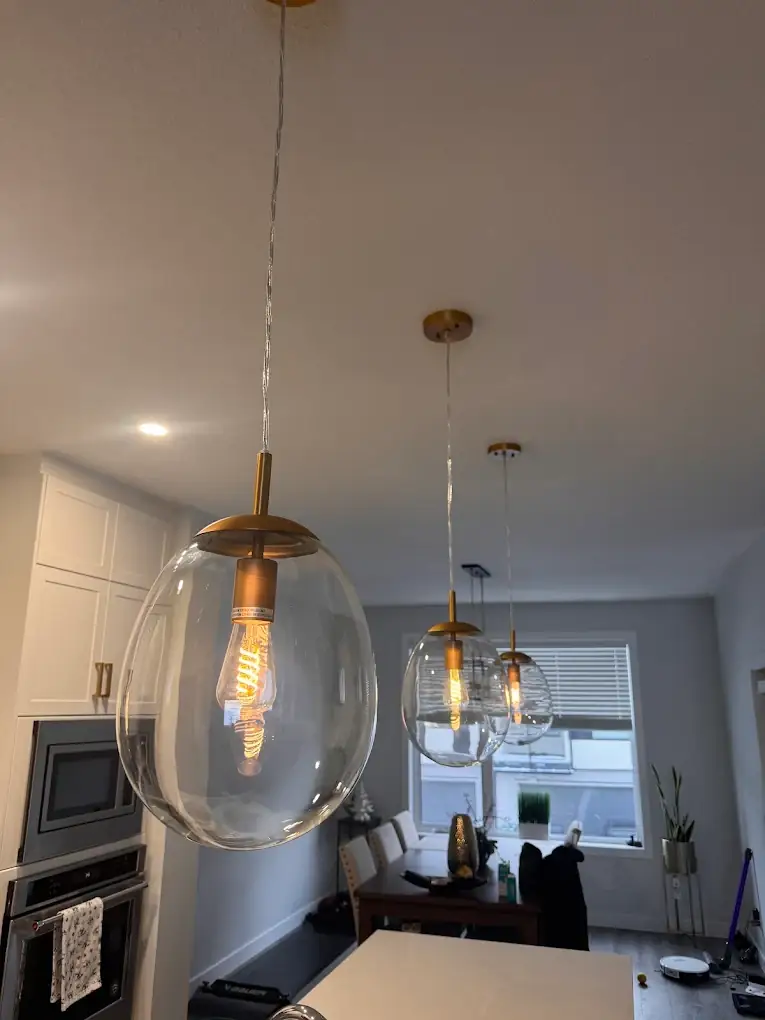 Three gold globe pendant lights over a kitchen island