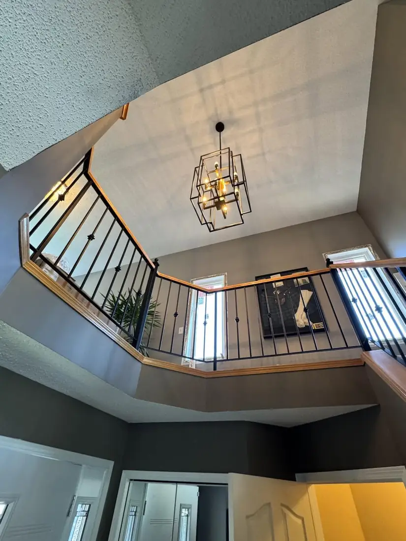 Black cage chandelier hanging over an open stairwell