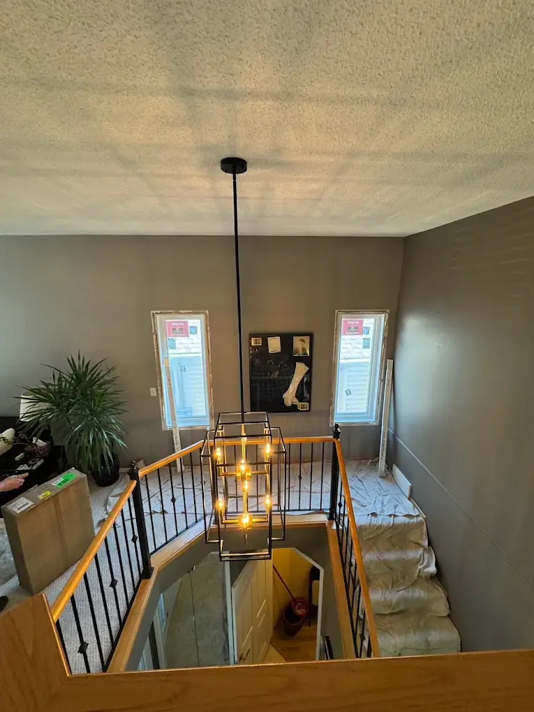 Black lantern pendant hanging in a two storey stairwell