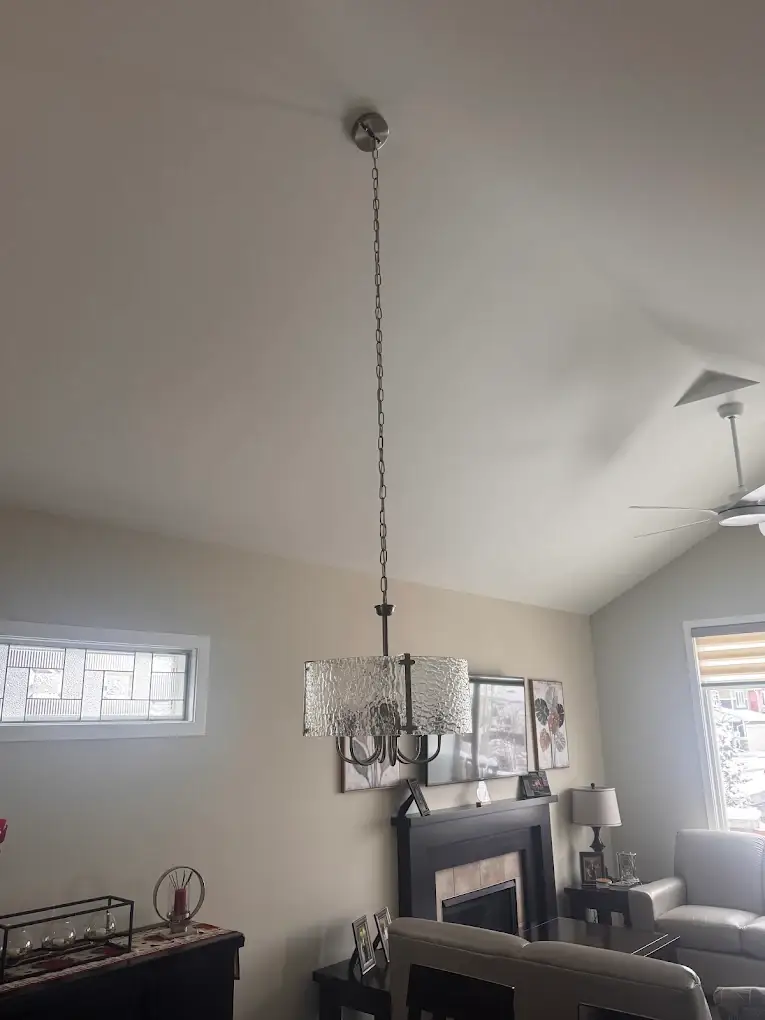 Chandelier hung on a long chain from a vaulted ceiling above a dining table